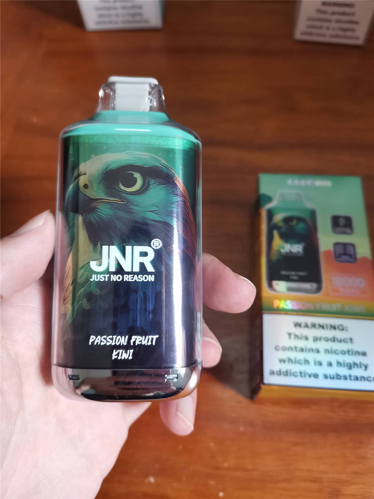 primer plano de una mano sosteniendo el passion fruit kiwi con sabor a jnr falcon 16k